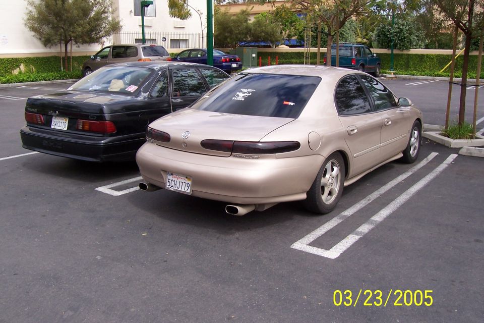Gold 1998 Mercury Sable sedan parked in a lot, rear view. License plate SCHJ779