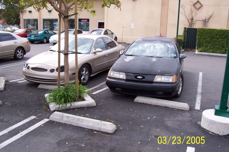 Black sedan front view, tan sedan parked next to it
