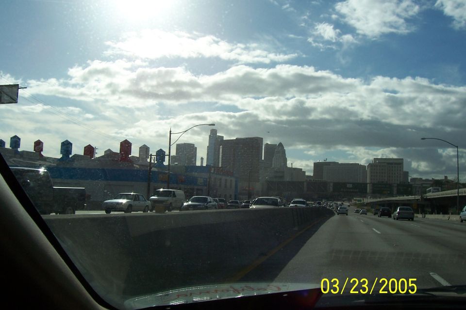 View of a city skyline from a highway with traffic. Date stamp reads 03/23/2005