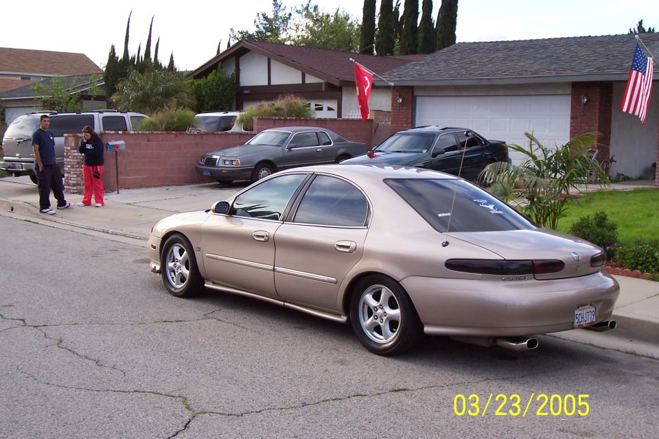Tan 1998 Mercury Sable sedan, rear 3/4 view, parked on street, dual exhaust pipes