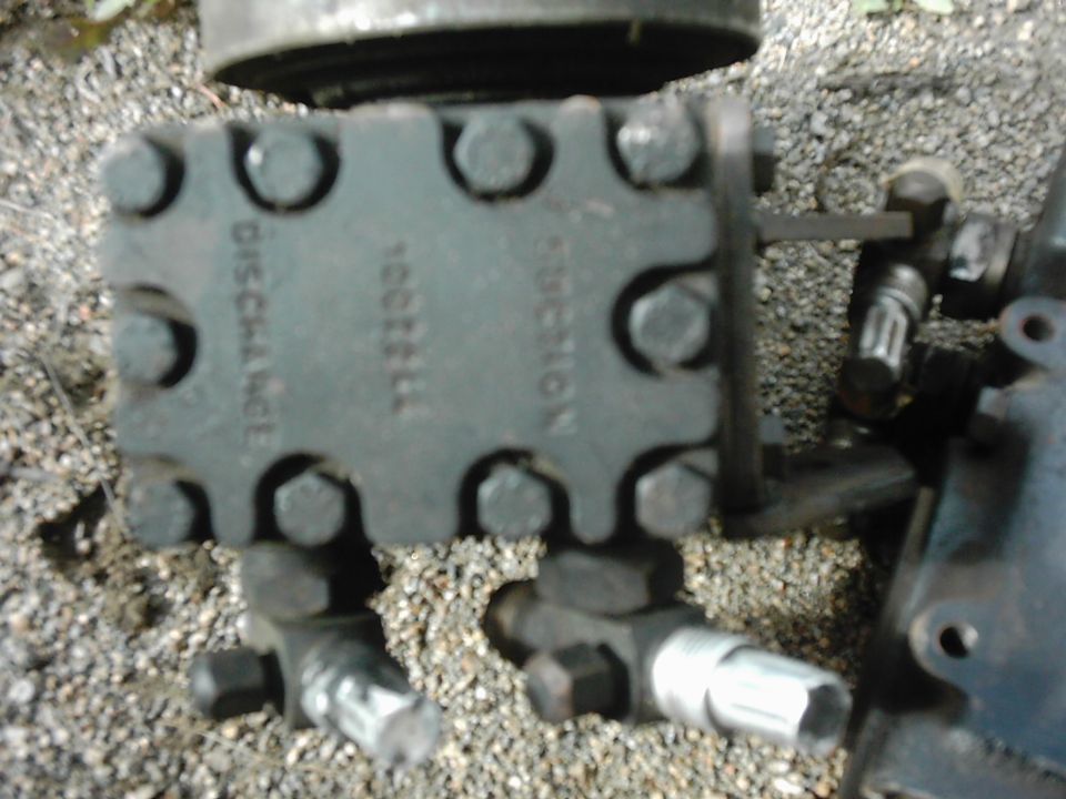 Close-up of a hydraulic pump with 'DISCHARGE' and 'SUCTION' labels visible