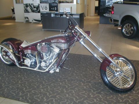 1979 Ford Bronco - A custom motorcycle with a distinctive maroon paint job and extensive chrome detailing is displayed indoors.