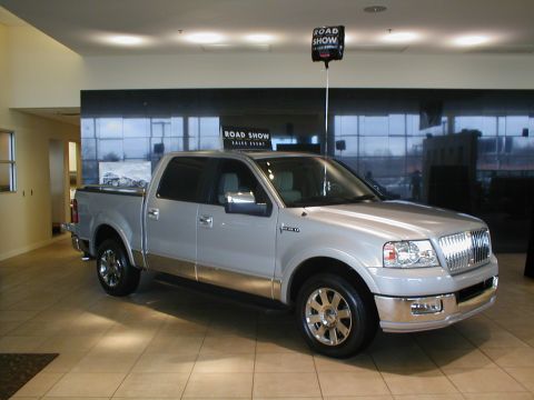 1979 Ford Bronco - A silver pickup truck is displayed indoors with a "Road Show Sales Event" sign overhead.