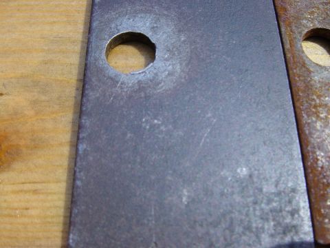 1988 Ford Bronco - Close-up of a metal plate with a hole, possibly undergoing rust removal or repair.