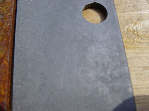 1988 Ford Bronco - Close-up of a rusted metal bracket with a hole, placed on a wooden surface.