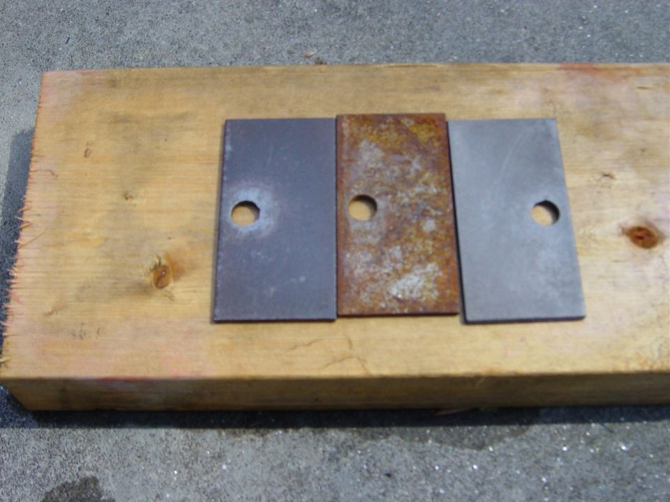 Three metal plates, one rusted, on a wooden plank. Text 'SUPERMOTORS' visible