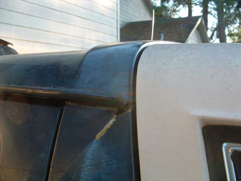 1993 Ford Bronco - A close-up view highlights the seam between two body panels on a vehicle, with a textured white panel adjacent to a dark panel.