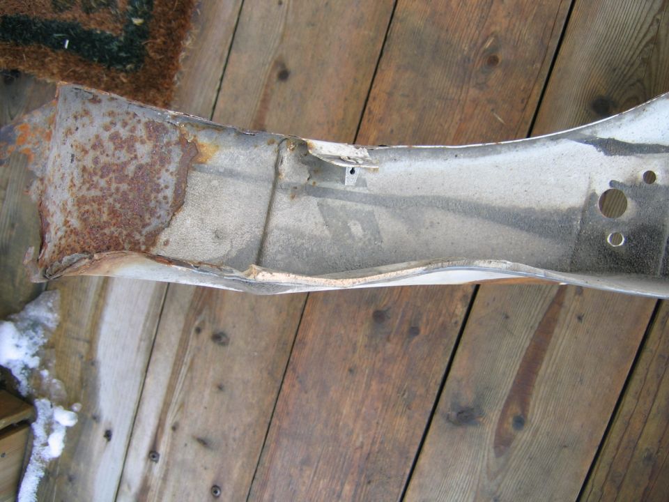 Rusted, bent metal car part on wooden planks with snow