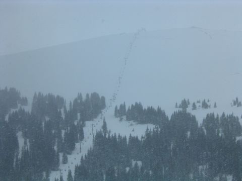 1992 Ford Probe - A ski lift traverses a snowy mountain slope, surrounded by dense evergreen trees.