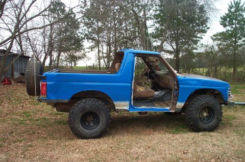1987 Ford Bronco - Blue 1987 Ford Bronco parked outdoors with the driver's door open.