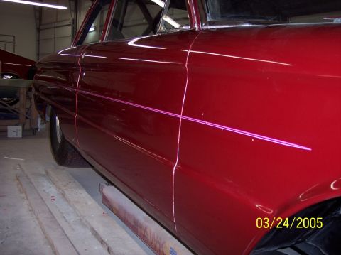 1960 Ford Falcon - The side panel of a red 1960 Ford Falcon displays a fresh coat of paint and subtle pinstriping.
