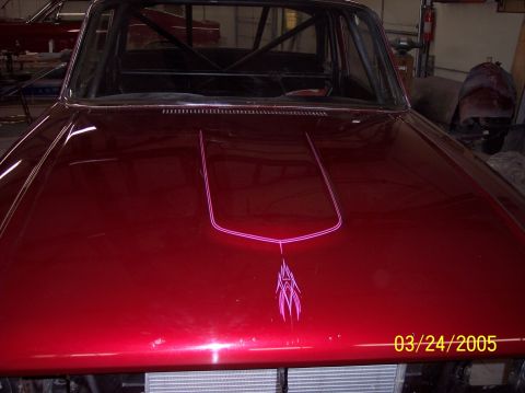 1960 Ford Falcon - The hood of a red car features custom pink pinstriping and a roll cage is visible through the windshield.