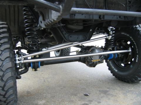 1992 Ford Bronco - Ground-level view under the front of a lifted Ford truck showing the Twin Traction Beam axle with a Dynatrac differential cover, heavy poli…
