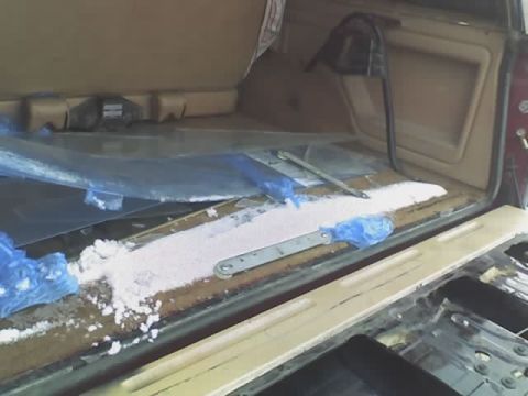 1985 Ford Bronco - The cargo area of a vehicle appears to be undergoing some sort of work or cleaning, with debris present.