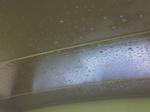 1985 Ford Bronco - Water droplets are visible on the interior ceiling of a vehicle, with a yellow trim piece running across.