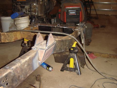 1992 Ford Bronco - Welding modifications being performed on a vehicle's frame, supported by jack stands.