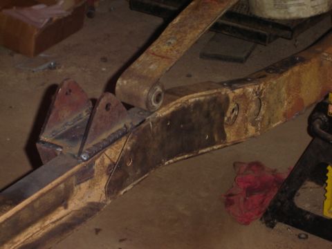1992 Ford Bronco - Close-up of a rusty vehicle frame section with a leaf spring, indicating repair work and wear.