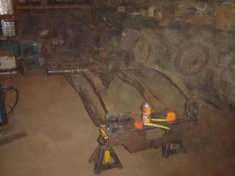 1992 Ford Bronco - A vehicle's frame is supported by jack stands, with a spray can and tape measure nearby.