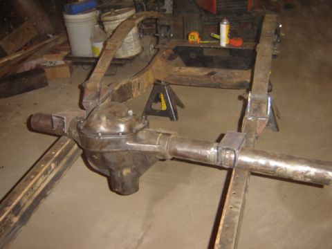 1992 Ford Bronco - Rear axle assembly with leaf spring mounts is shown on jack stands in a workshop.