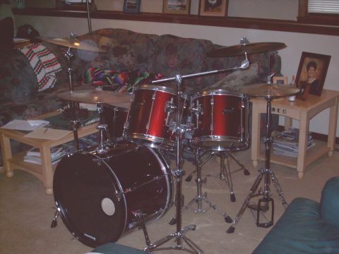 1986 Ford Bronco - A red drum set is set up in a room with a couch and end table in the background.