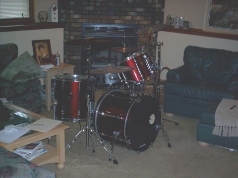 1986 Ford Bronco - A drum set is set up in a room with a fireplace, couch, and coffee table.