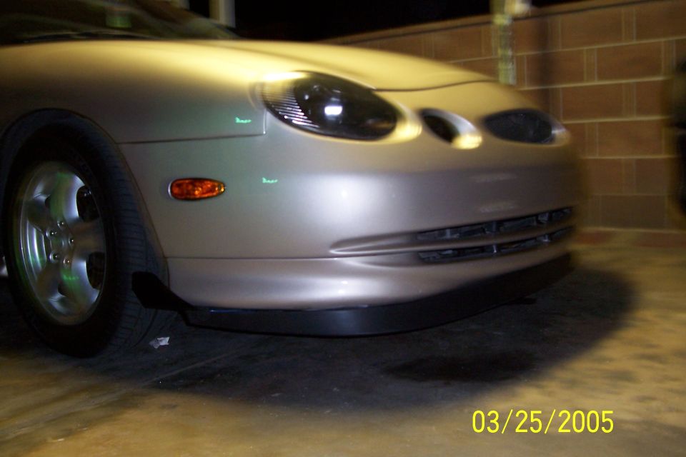 Silver sedan front bumper and headlight, low angle view