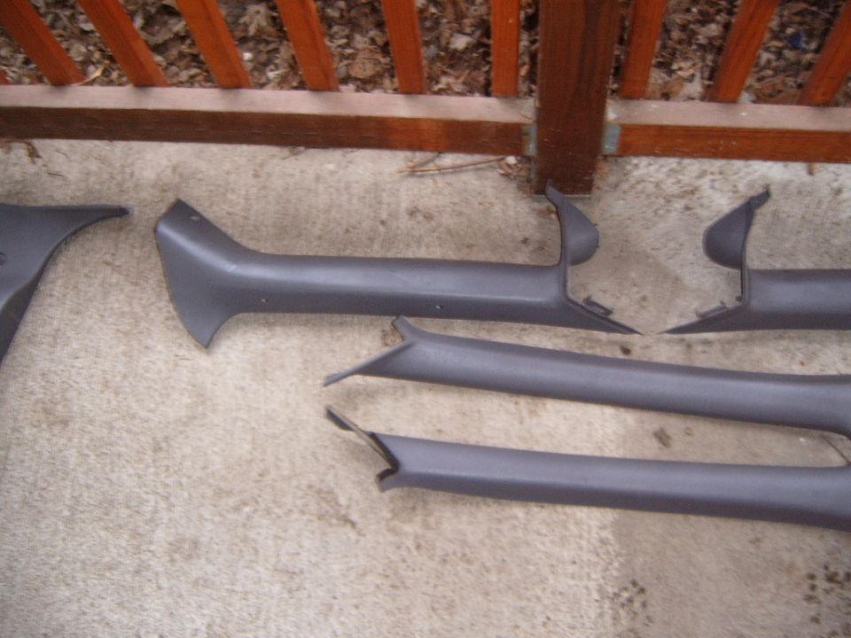 Gray plastic interior pillar and sill trim panels laid out on concrete patio