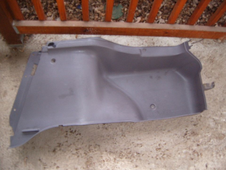 Gray plastic trunk interior trim panel on concrete ground