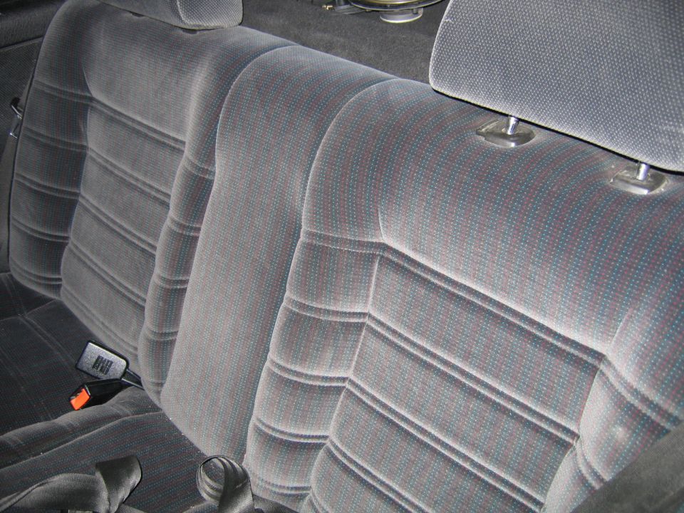 Back seat of a car with gray patterned fabric upholstery and headrests