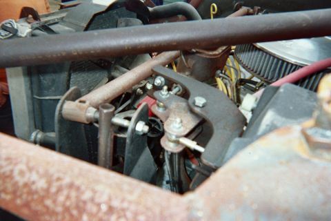 1990 Ford Bronco - Detailed view inside an engine bay showing the radiator, round air filter, throttle linkage and red wiring with surface rust on components.