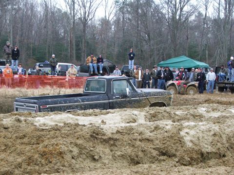 1996 Ford Bronco - Spectators watch as a pickup truck gets stuck in the mud at an off-road event.