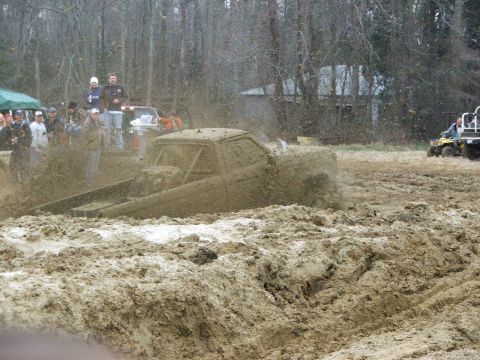 1996 Ford Bronco - A heavily modified truck churns through a mud bog as onlookers watch from the sidelines.