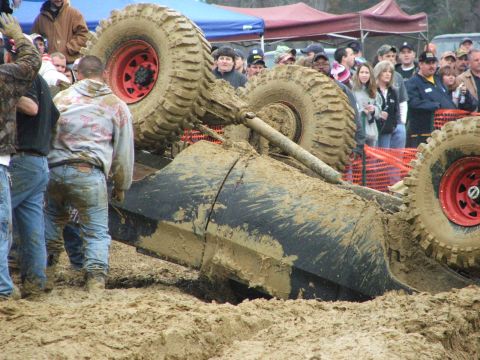 1996 Ford Bronco - A crowd watches as a heavily modified off-road vehicle is overturned in the mud during a bogging event.