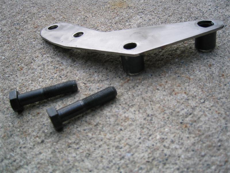 Bare steel triangular mounting bracket with welded spacers and two hex bolts on concrete