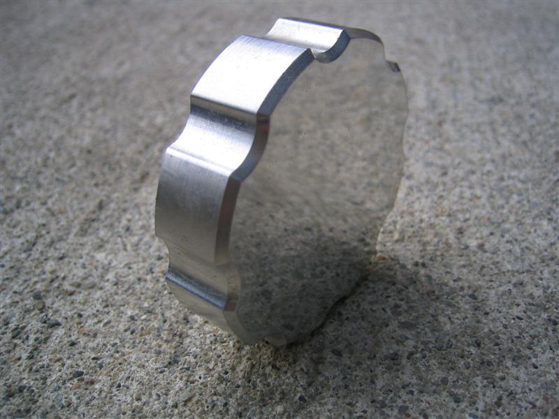 Machined aluminum ring spacer with scalloped edge standing on a concrete surface