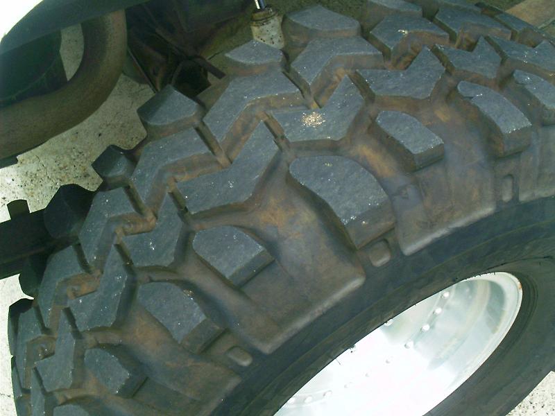 Close-up of dirty mud-terrain tire tread on a polished aluminum wheel