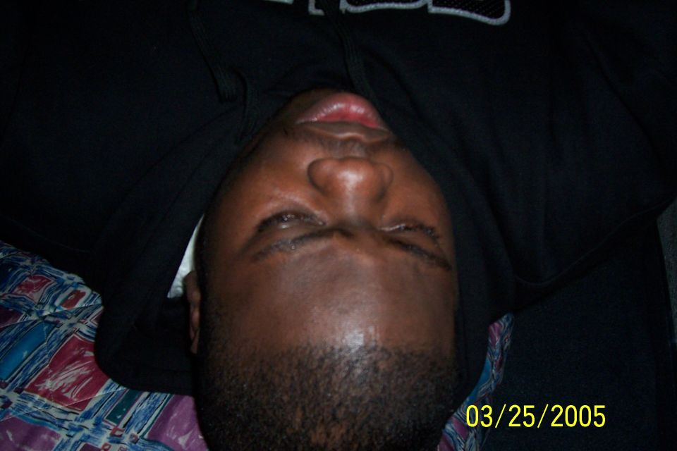 Man in black hoodie lying down, eyes open, looking up. Date stamp in corner