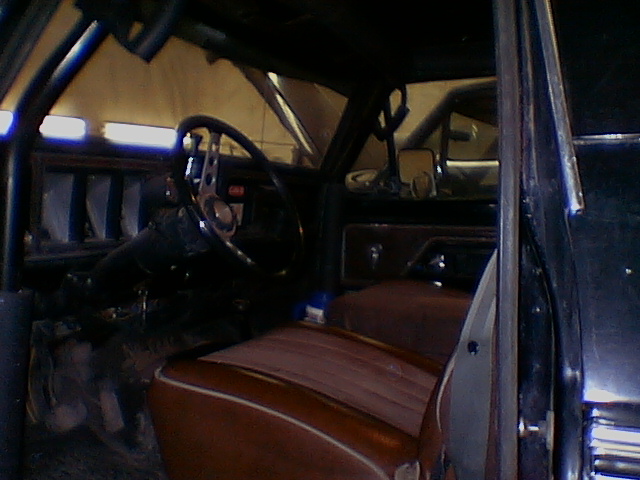 Interior view of an SUV with a roll cage and brown seats. Another vehicle is visible through the window