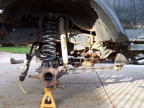 1994 Ford F-150 - The front suspension components of a vehicle are shown disassembled and supported by jack stands.