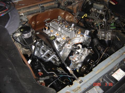 1990 Ford Bronco - Overhead view of a V8 sitting in a truck's brown engine bay during installation, showing the aluminum lower intake with fuel injectors and…