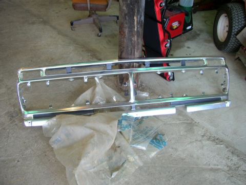 1995 Ford Bronco - A detached chrome grille is shown on a concrete surface, partially covered by plastic sheeting.