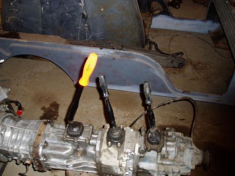 1992 Ford Bronco - A transmission with three shifters is visible, along with a yellow-handled screwdriver.