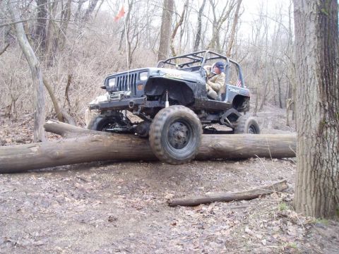 1992 Ford Bronco - Off-road Jeep Wrangler navigates a fallen tree during a test run in a wooded area.