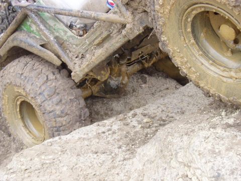 1992 Ford Bronco - This off-road vehicle is deeply stuck in mud and dirt, with its tires partially submerged.