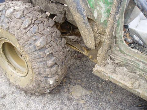1992 Ford Bronco - Close-up of a heavily soiled off-road vehicle's tire and undercarriage, suggesting recent use in rough terrain.