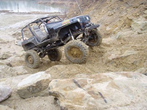 1992 Ford Bronco - A black Jeep Wrangler navigates a challenging off-road course with steep inclines and rocky terrain.