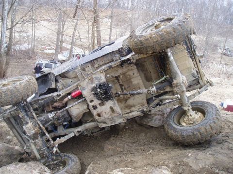 1992 Ford Bronco - An off-road vehicle has rolled onto its side during an off-road excursion, with another vehicle nearby.