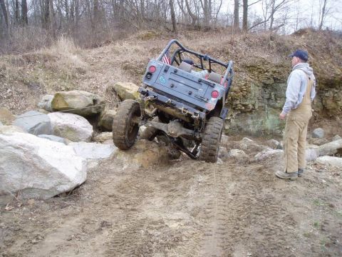 1992 Ford Bronco - An off-road vehicle navigates a challenging rocky course, with a person observing the action.