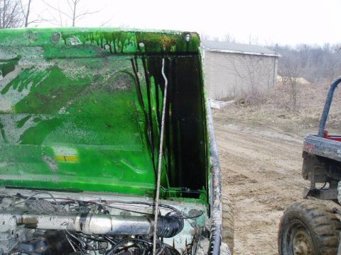 1992 Ford Bronco - Interior of a green vehicle hood shows dripping black fluid; another vehicle is partially visible.