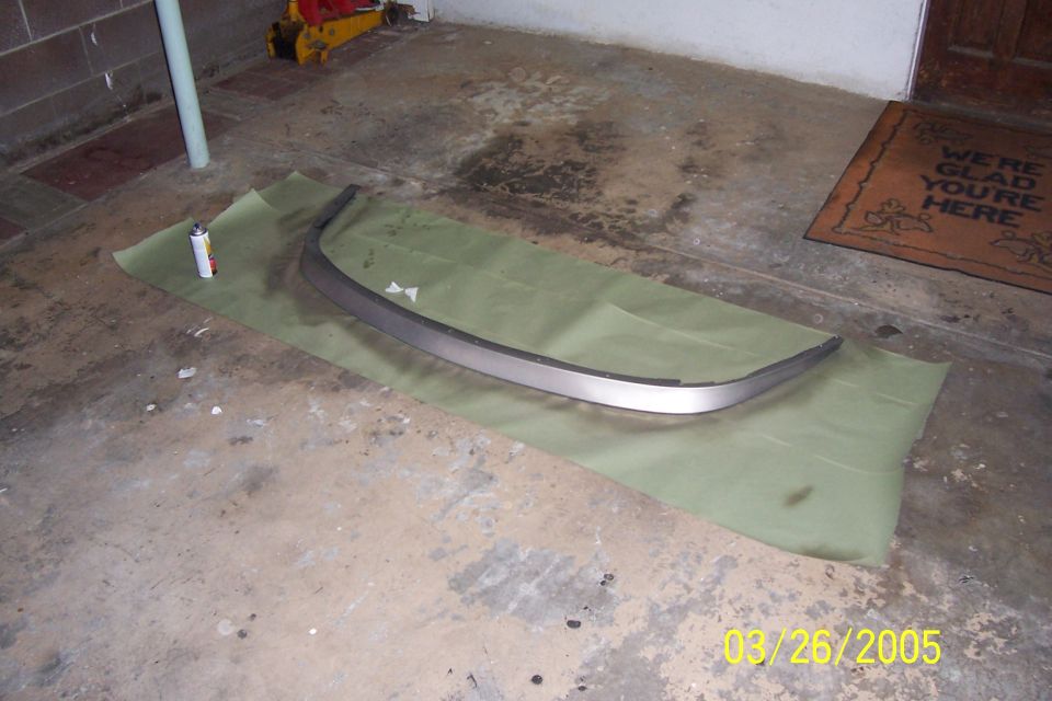 Silver car trim piece on green paper with spray can